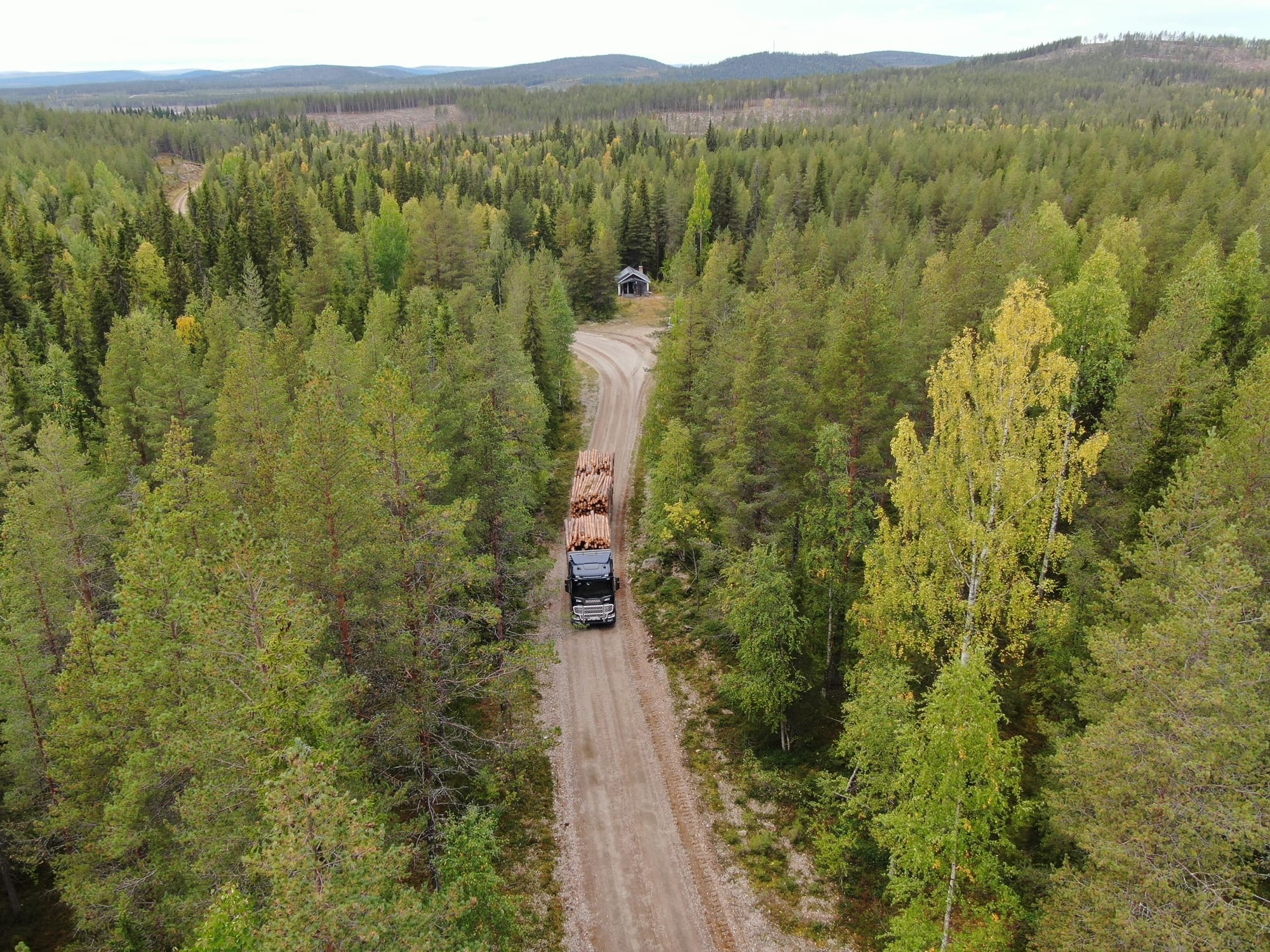 Timmerbil på skogsväg i Norrbotten – flygfoto